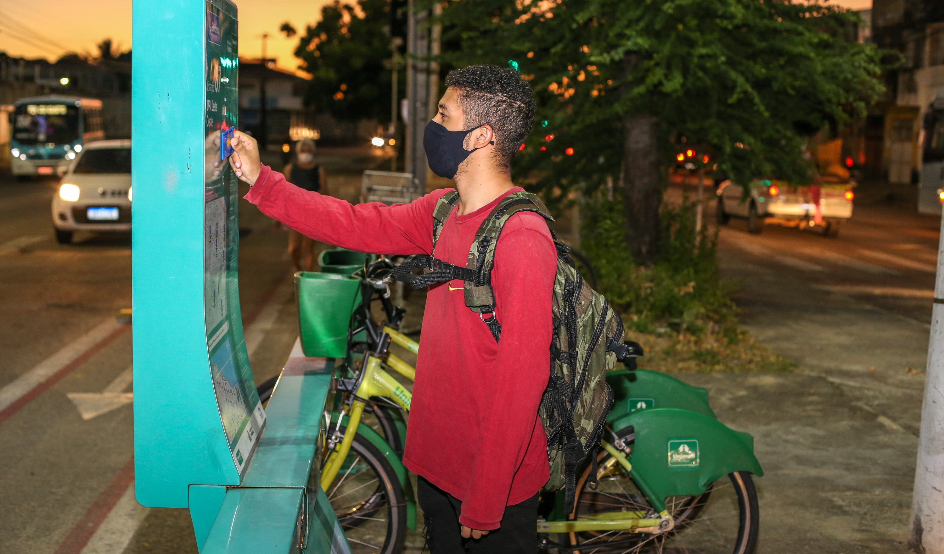 rapaz retira uma bicicleta numa estação do bicletar